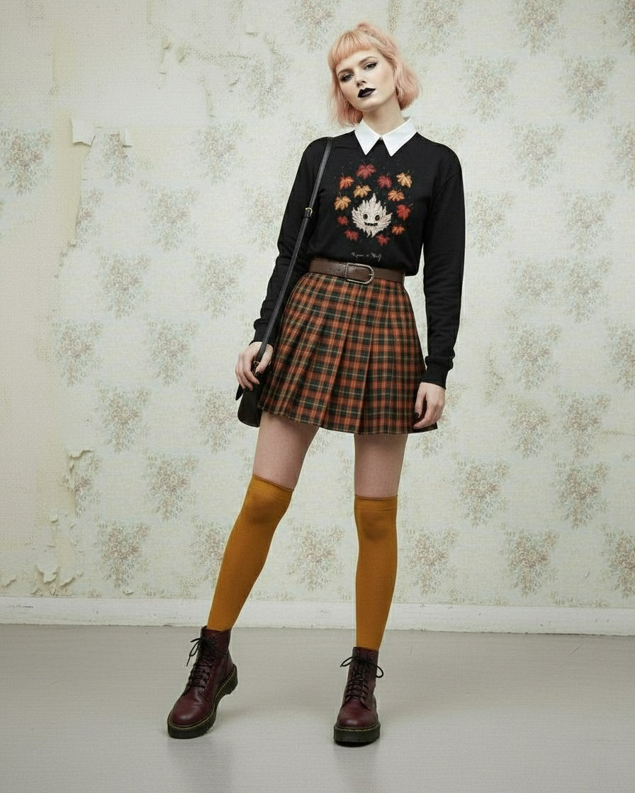 Person wearing a black sweater with a floral design, plaid skirt, yellow knee-high socks, and brown boots against a patterned wall.