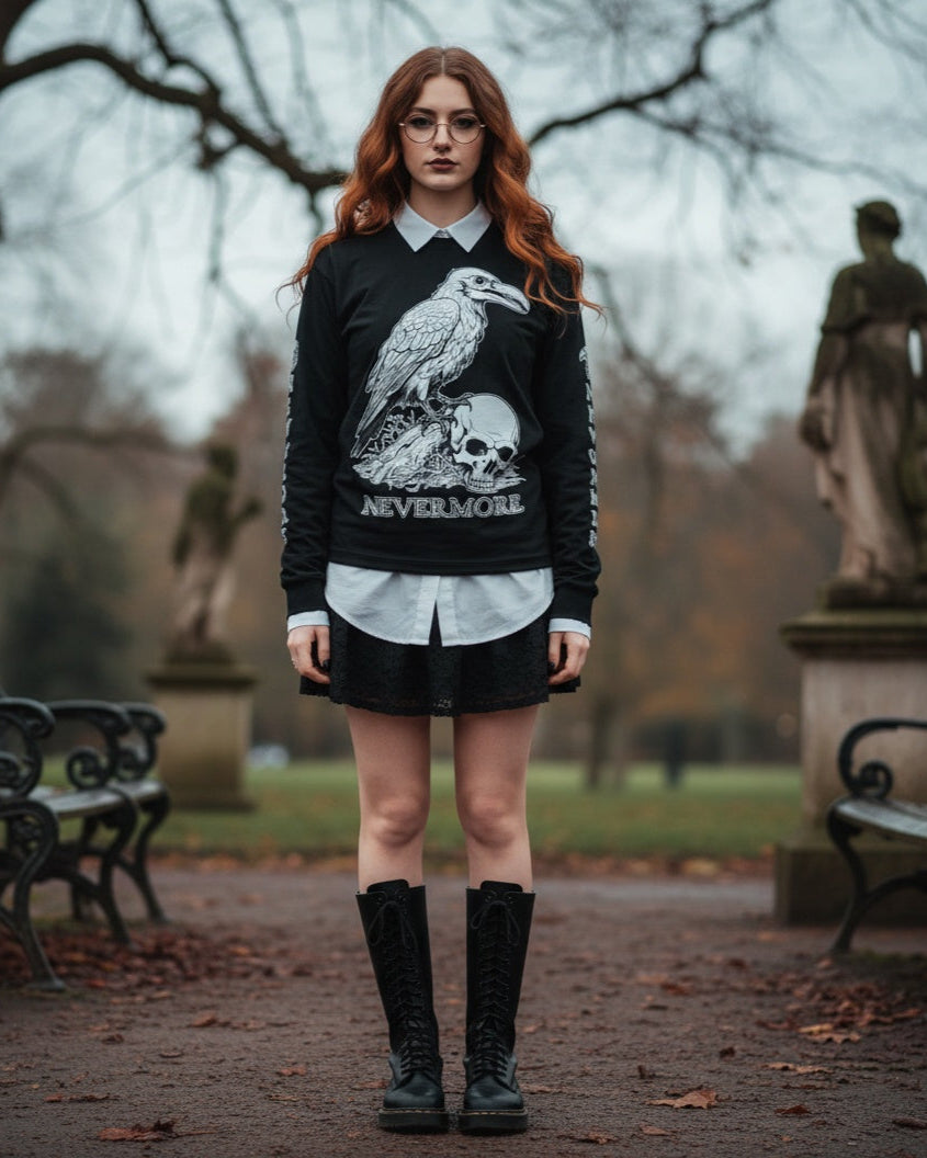 Person wearing a black sweater with a raven and skull design, standing in an outdoor setting with statues and benches.