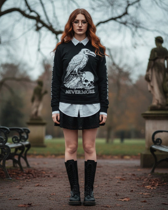 Person wearing a black sweater with a raven and skull design, standing in an outdoor setting with statues and benches.