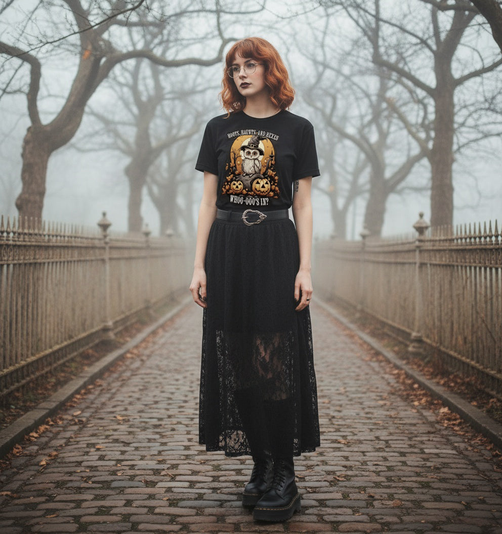 Person wearing a black t-shirt with graphic design and a long black skirt in a foggy park.
